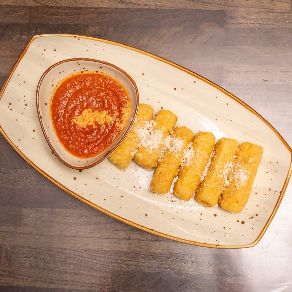 Golden-brown mozzarella sticks with grated cheese and a side of marinara sauce on a speckled plate.