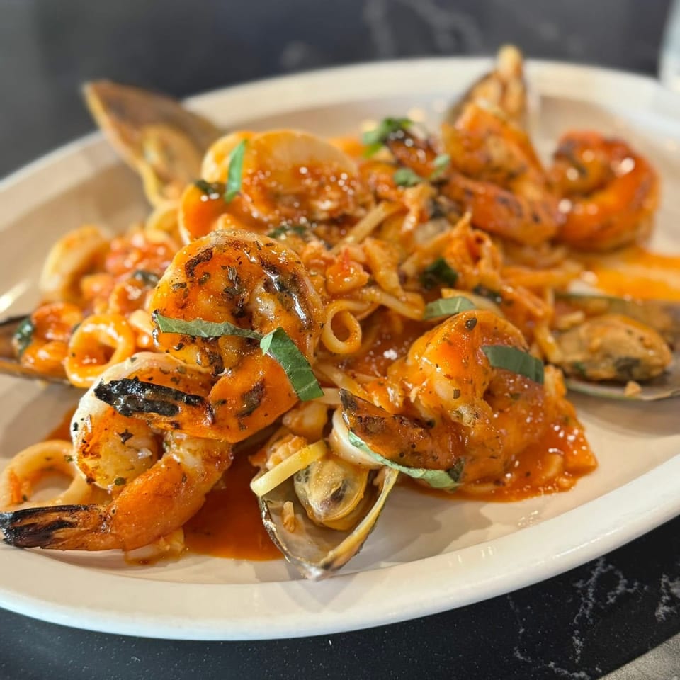 Seafood pasta with shrimp, mussels, and calamari in a red sauce, garnished with basil.