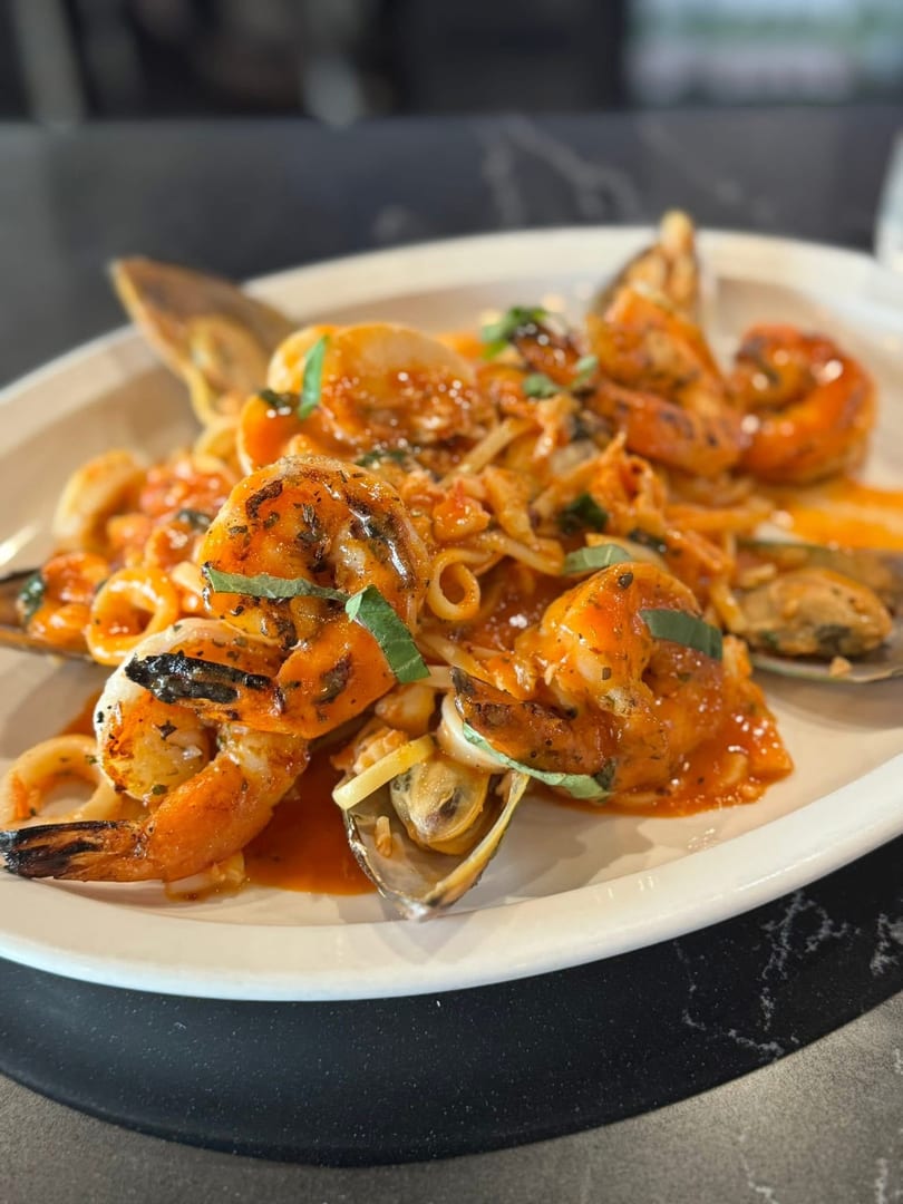 Seafood pasta with shrimp, mussels, and calamari in a red sauce, garnished with basil.